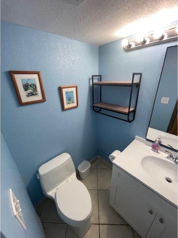 bathroom featuring a textured wall, toilet, tile patterned flooring, a textured ceiling, and vanity