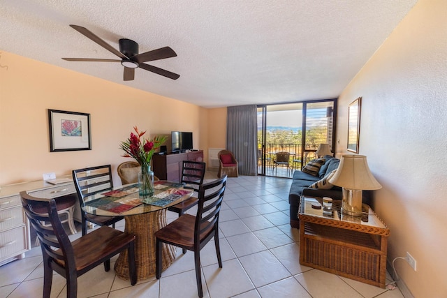 dining space featuring expansive windows, light tile patterned flooring, ceiling fan, and a textured ceiling