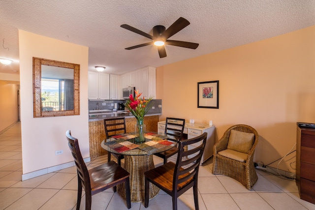 dining room featuring light tile patterned floors, ceiling fan, baseboards, and a textured ceiling