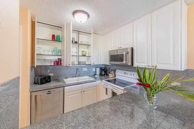 kitchen featuring a textured ceiling, stainless steel appliances, a sink, white cabinetry, and open shelves