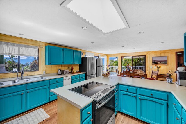 kitchen with freestanding refrigerator, light wood-style flooring, a sink, light countertops, and range with electric stovetop