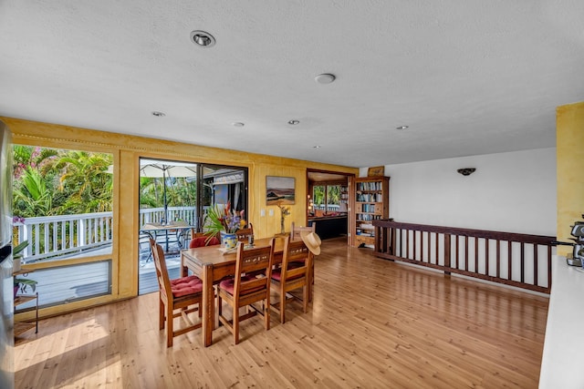 dining space featuring a textured ceiling, light wood-type flooring, and a healthy amount of sunlight