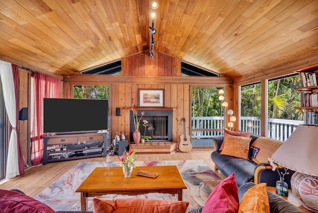 living area with a fireplace with raised hearth, wood ceiling, wooden walls, wood finished floors, and vaulted ceiling with beams