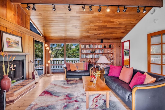 living room with vaulted ceiling, track lighting, wood walls, wooden ceiling, and wood finished floors