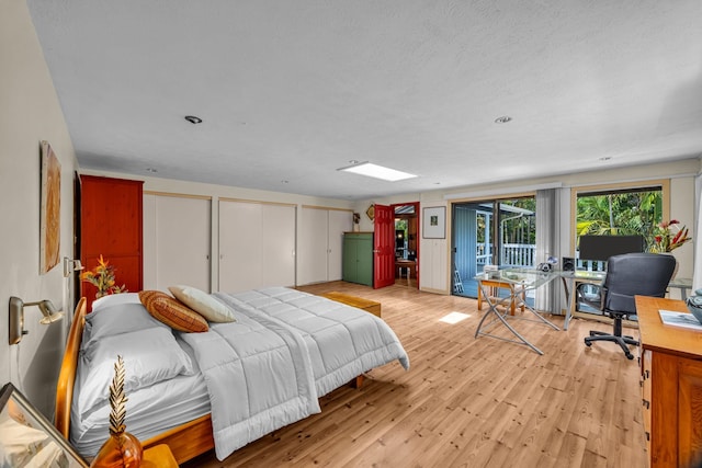 bedroom with access to outside, multiple closets, and light wood-style floors