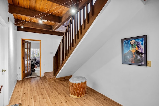 stairway featuring beam ceiling, wooden ceiling, and hardwood / wood-style flooring