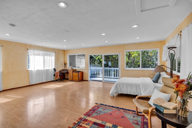 bedroom featuring light wood-style flooring, access to outside, attic access, and recessed lighting
