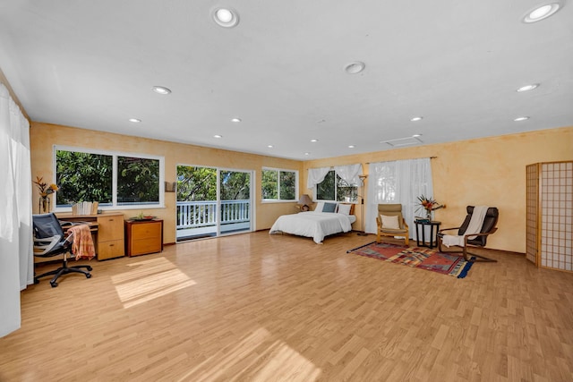 bedroom with wood finished floors, access to exterior, and recessed lighting