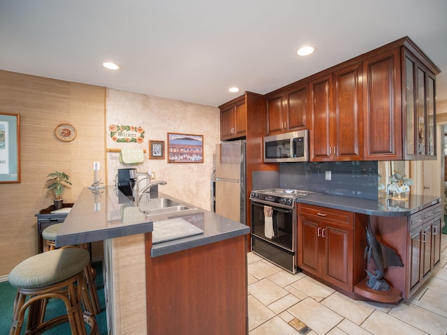 kitchen featuring a kitchen breakfast bar, kitchen peninsula, black electric range, sink, and refrigerator