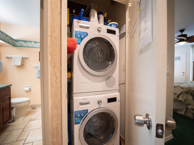 washroom with light tile patterned floors, stacked washer and dryer, and ceiling fan