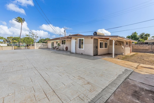 view of front facade featuring stucco siding, a patio, and fence