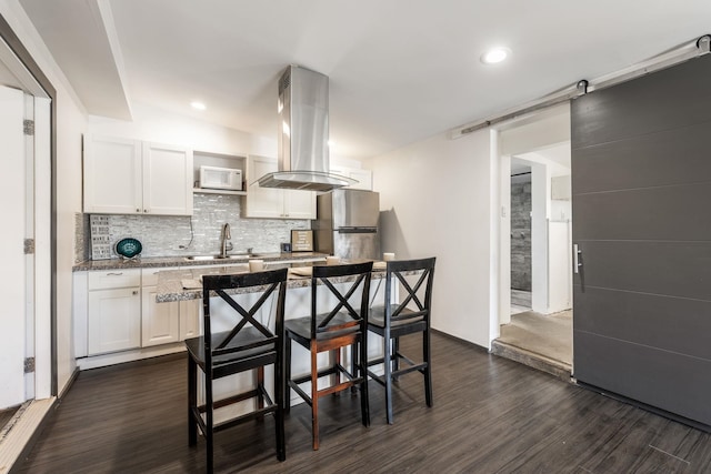 kitchen featuring tasteful backsplash, island exhaust hood, freestanding refrigerator, dark wood-style floors, and white cabinets