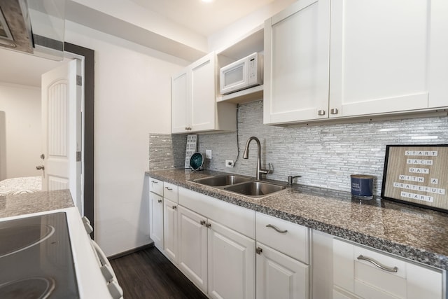 kitchen with white microwave, dark wood-style flooring, a sink, white cabinetry, and backsplash