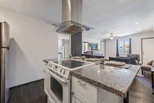 kitchen with white range with electric cooktop, island exhaust hood, dark wood finished floors, freestanding refrigerator, and ceiling fan