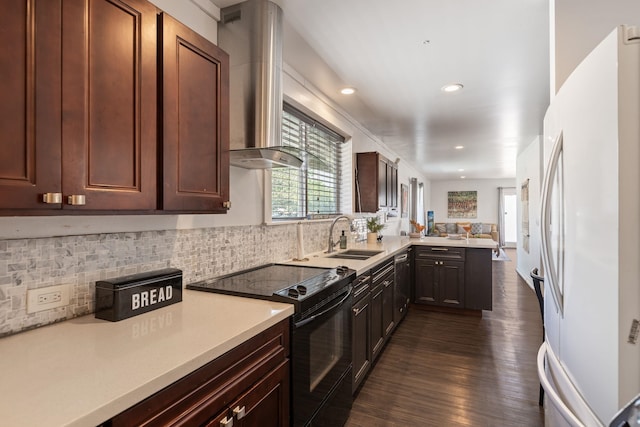 kitchen with a peninsula, freestanding refrigerator, a sink, light countertops, and black electric range