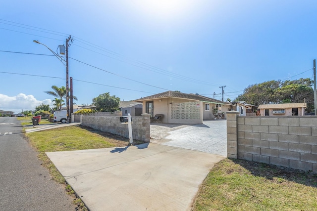 ranch-style home with a fenced front yard, driveway, and stucco siding