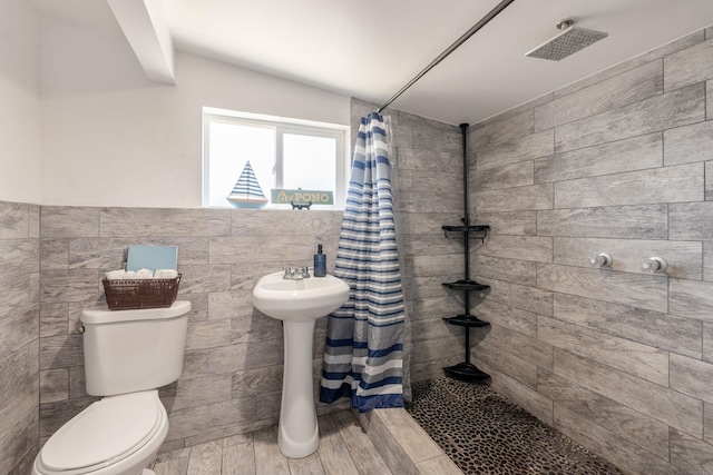 bathroom with tiled shower, toilet, tile walls, and wood tiled floor