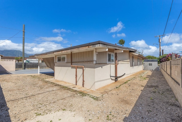 view of side of home with a storage unit, an outbuilding, and a fenced backyard