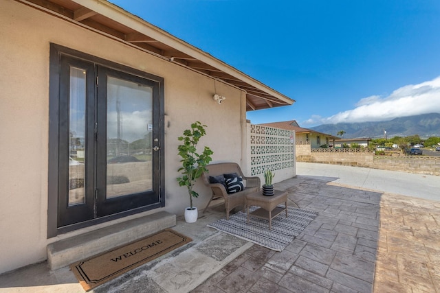 entrance to property featuring stucco siding, a mountain view, and a patio area