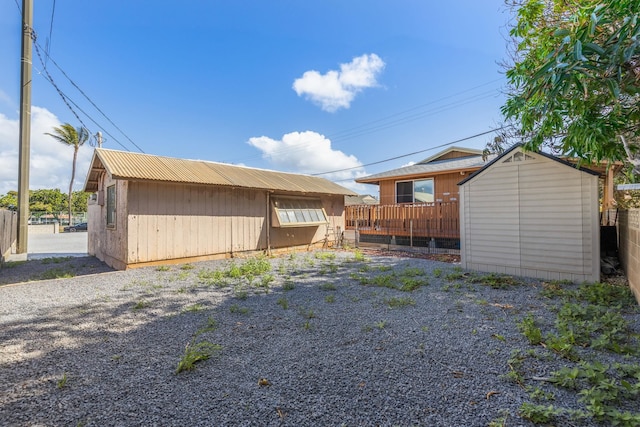 rear view of house featuring a storage shed, an outdoor structure, and fence