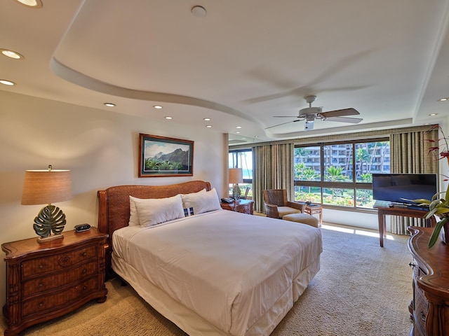 bedroom with light carpet, a raised ceiling, and ceiling fan