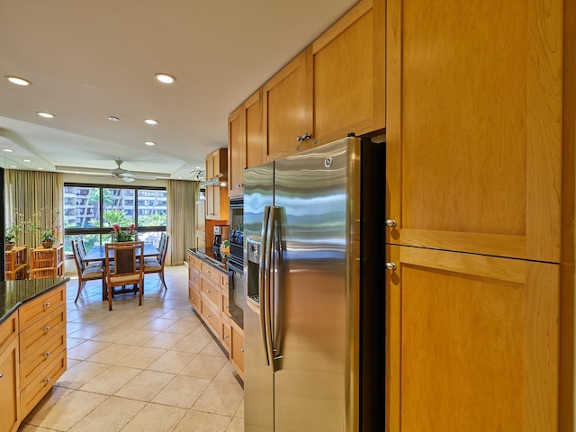 kitchen with ceiling fan, stainless steel refrigerator with ice dispenser, dark stone countertops, black oven, and light tile patterned flooring