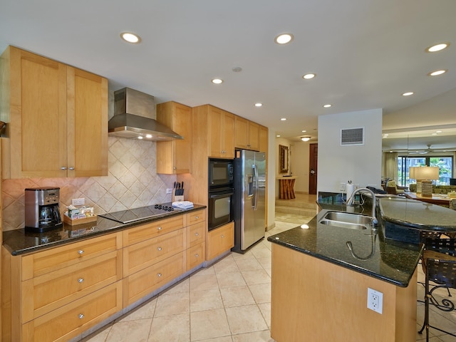 kitchen featuring dark stone counters, black appliances, sink, wall chimney exhaust hood, and light tile patterned flooring