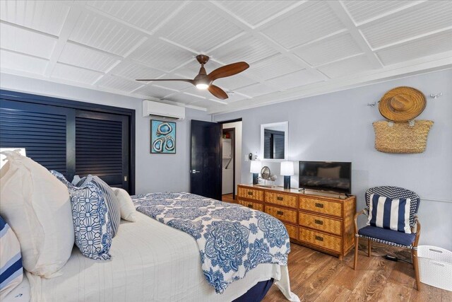 bedroom with an AC wall unit, hardwood / wood-style flooring, and ceiling fan