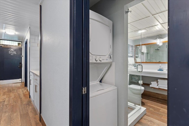 laundry area featuring stacked washer / drying machine and light wood-type flooring