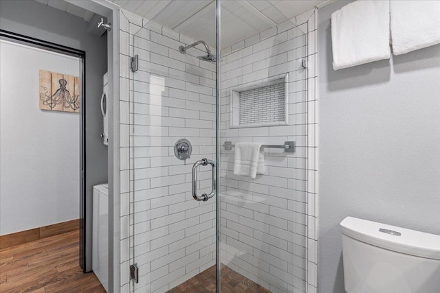 bathroom with wood-type flooring, toilet, and a shower with door