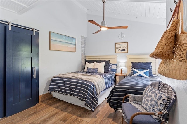 bedroom with lofted ceiling, a barn door, ceiling fan, and wood-type flooring