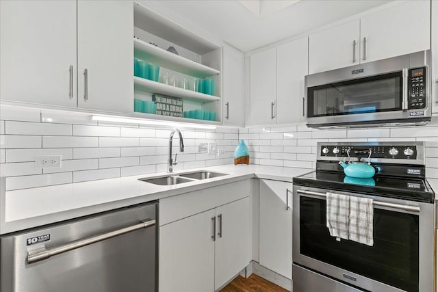 kitchen with backsplash, white cabinets, sink, and stainless steel appliances