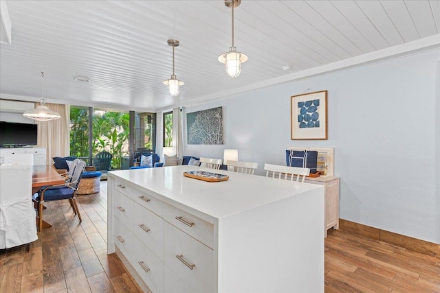 kitchen featuring a kitchen island, white cabinetry, light wood-type flooring, and decorative light fixtures