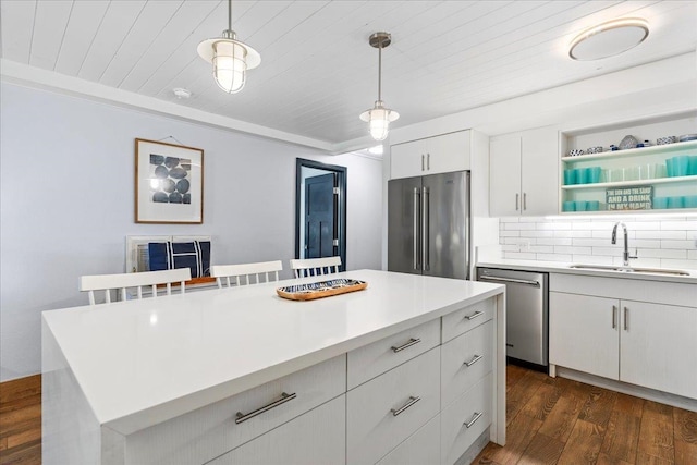 kitchen with stainless steel appliances, dark hardwood / wood-style flooring, sink, pendant lighting, and white cabinetry