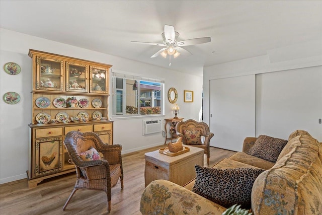 living room featuring ceiling fan, a wall mounted air conditioner, and light wood-type flooring