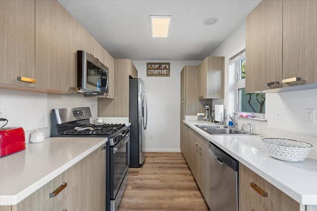 kitchen featuring sink, light wood-type flooring, light brown cabinets, and appliances with stainless steel finishes