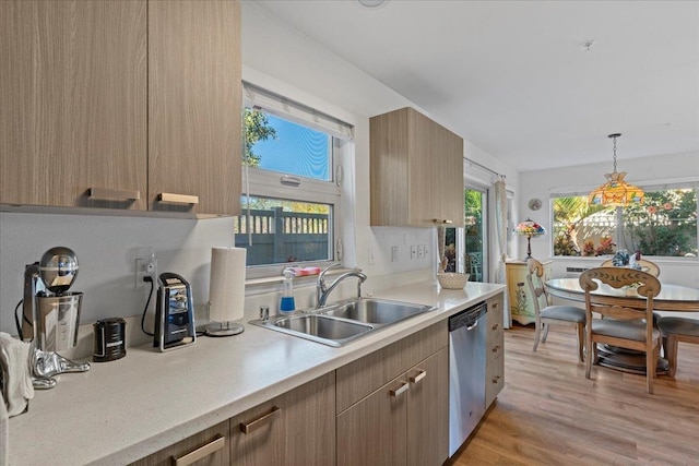 kitchen with dishwasher, sink, hanging light fixtures, and light hardwood / wood-style flooring