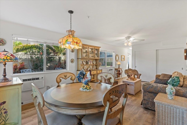 dining room featuring light hardwood / wood-style floors, an AC wall unit, and a wealth of natural light