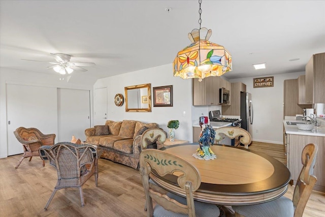 dining room featuring ceiling fan, sink, and light hardwood / wood-style floors