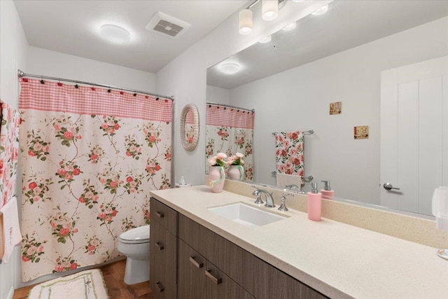 bathroom featuring walk in shower, vanity, wood-type flooring, and toilet