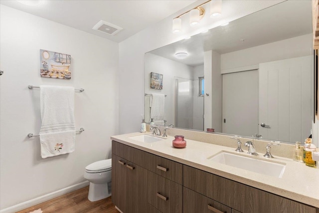 bathroom with vanity, toilet, wood-type flooring, and a shower with door