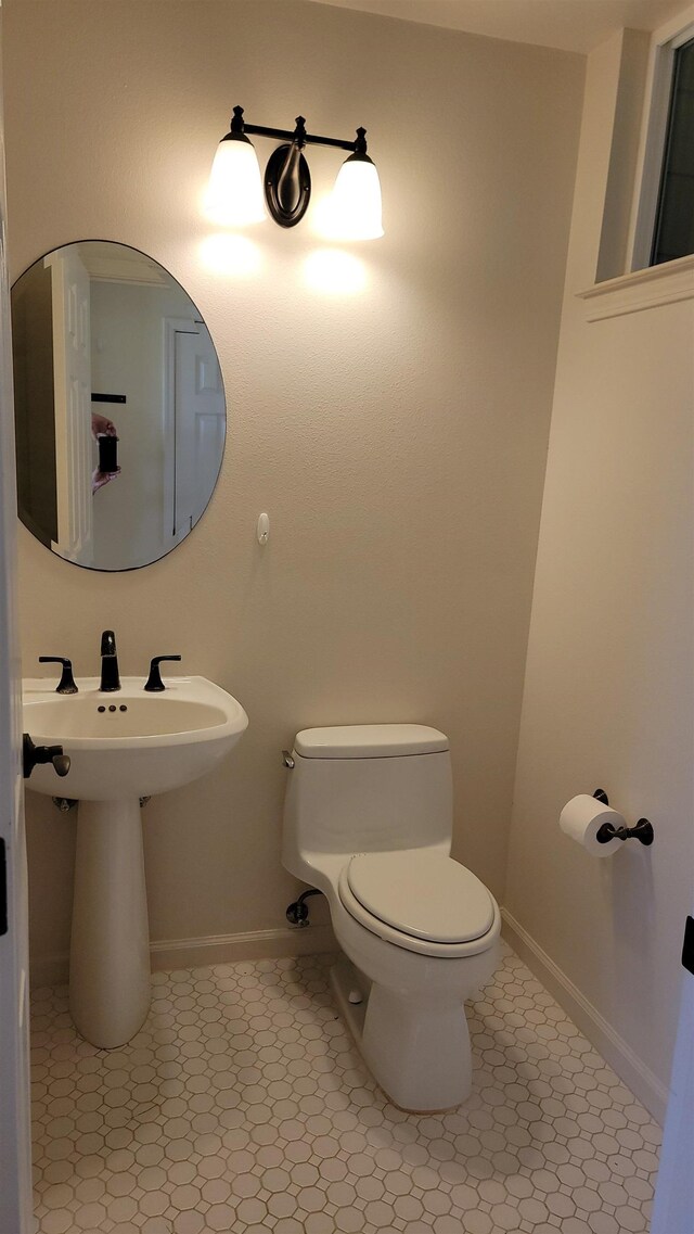 half bathroom with toilet, tile patterned floors, and baseboards