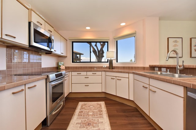 kitchen with sink, stainless steel appliances, dark hardwood / wood-style flooring, tile countertops, and white cabinets