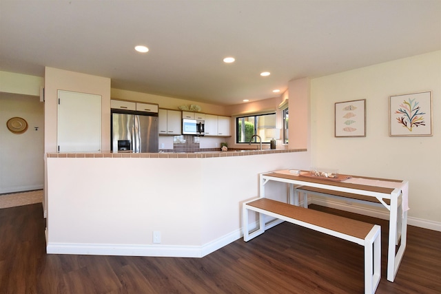 kitchen with dark hardwood / wood-style flooring, white cabinetry, kitchen peninsula, and appliances with stainless steel finishes