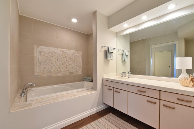 bathroom with vanity, wood-type flooring, and a relaxing tiled tub