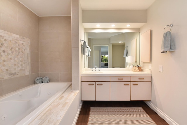 bathroom with wood-type flooring, vanity, and tiled tub