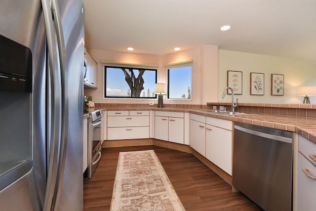 kitchen featuring dark wood-type flooring, sink, appliances with stainless steel finishes, tile counters, and white cabinetry