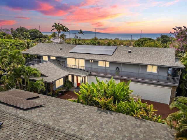 view of front of house with a water view, solar panels, and a garage