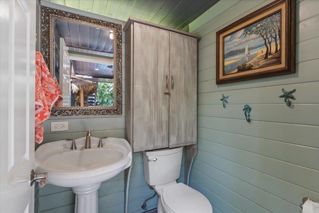 bathroom featuring wooden walls, toilet, and wooden ceiling