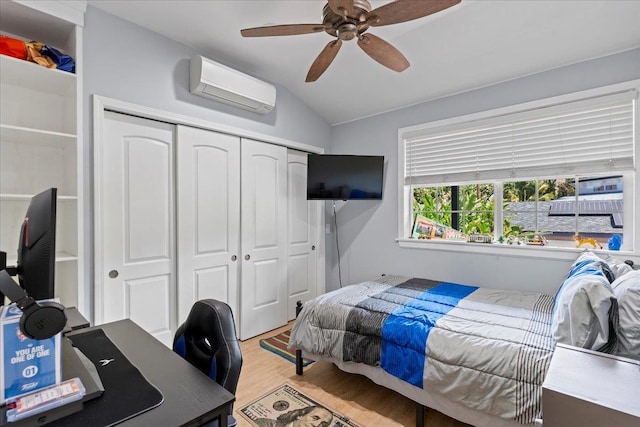 bedroom featuring a wall mounted air conditioner, a closet, light hardwood / wood-style flooring, and ceiling fan